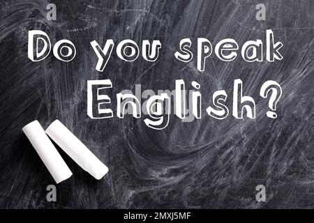 Pieces of white chalk and question DO YOU SPEAK ENGLISH written on blackboard, flat lay Stock Photo