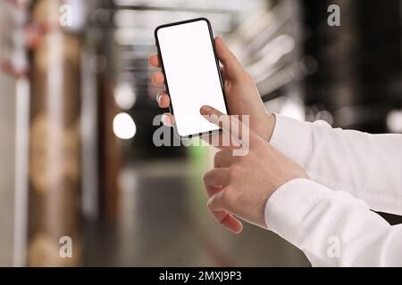 Wholesale trading. Man using WMS app on smartphone at warehouse, closeup Stock Photo