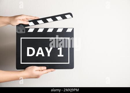 Starting new life chapter. Woman holding clapperboard with text Day 1, closeup Stock Photo