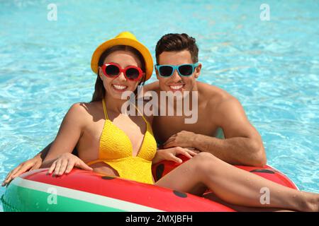 Happy couple with inflatable ring in swimming pool. Summer vacation Stock Photo