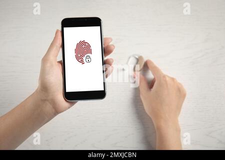 Set up hearing aid with smartphone app, fingerprint sensor on screen, top view. Digital identity Stock Photo