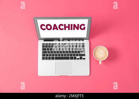 Business training or life coaching. Modern laptop and cup of coffee on pink background, flat lay Stock Photo