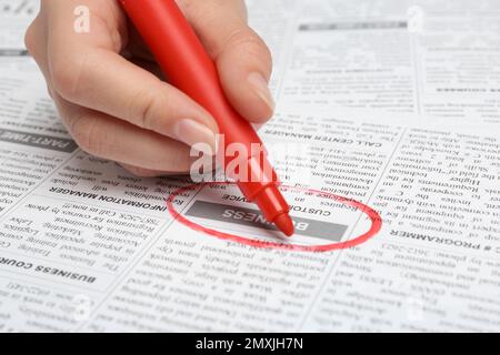 Woman marking advertisement in newspaper, closeup. Job search concept Stock Photo