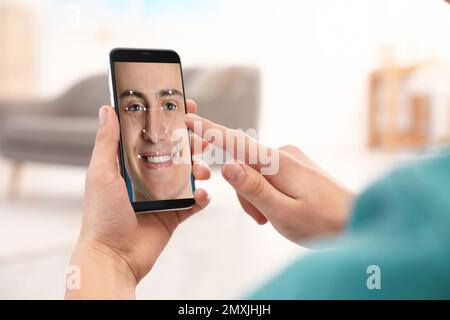 Man using smartphone with facial recognition system indoors, closeup. Biometric verification Stock Photo