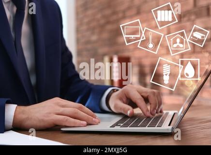 Man using laptop to control smart home, closeup. Automatic systems Stock Photo
