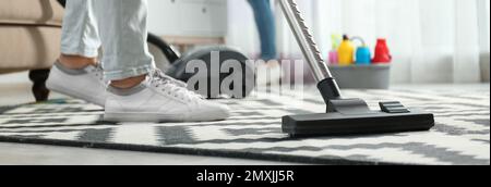Cleaning service worker vacuuming carpet indoors, closeup. Banner design Stock Photo