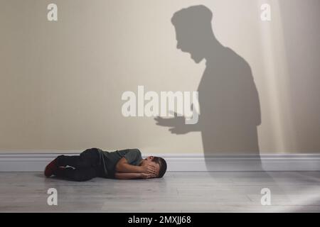 Child abuse. Father yelling at his son. Shadow of man on wall Stock Photo