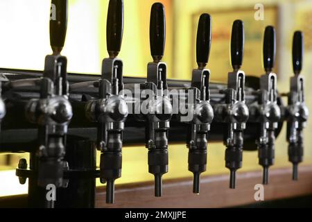 New modern beer taps in pub, closeup. Professional bar equipment Stock Photo