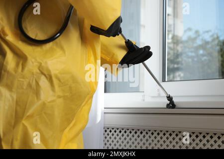 Pest control worker spraying pesticide on window sill indoors, closeup Stock Photo