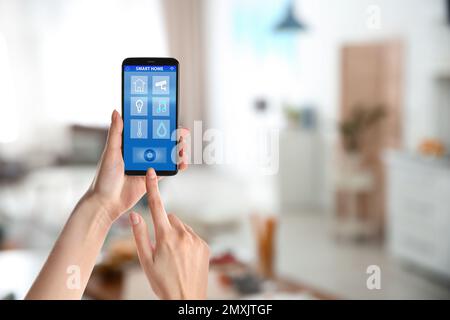 Woman using phone application for controlling smart home indoors, closeup Stock Photo