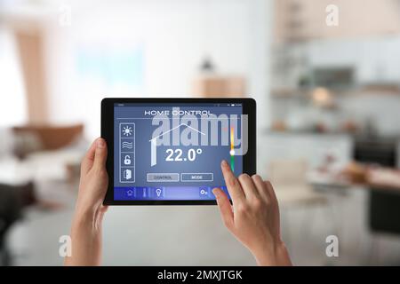 Woman using tablet to set indoor temperature, closeup. Smart home automation system Stock Photo