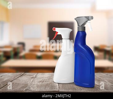 Protective measures during Coronavirus pandemic. Bottles of disinfectant on table against classroom, space for text Stock Photo