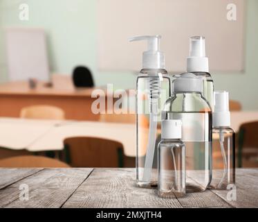 Protective measures during Coronavirus pandemic. Hand sanitizers on table against classroom, space for text Stock Photo
