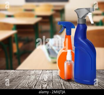 Protective measures during Coronavirus pandemic. Bottles of disinfectant and hand sanitizer on table against classroom, space for text Stock Photo