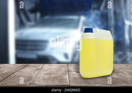 Plastic canister with cleaning liquid for vehicle on wooden surface at car wash. Space for text Stock Photo