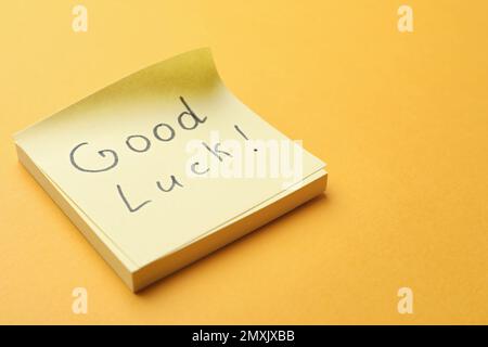 Note with phrase GOOD LUCK on orange background Stock Photo