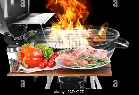 Modern flaming barbecue grill near uncooked food on black background, closeup Stock Photo