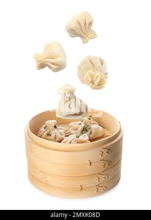 Many tasty dumplings falling into bamboo steamer on white background Stock Photo