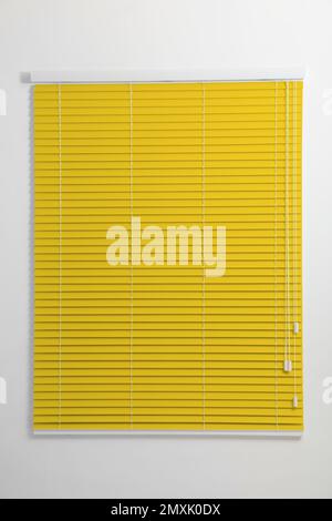 Window with closed yellow blinds in room Stock Photo