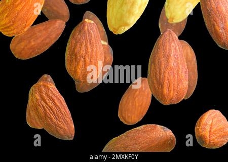 Falling almond isolated on a black background, selective focus. Almond nuts levitate on a black background. Freeze motion of flying whole almonds. Stu Stock Photo