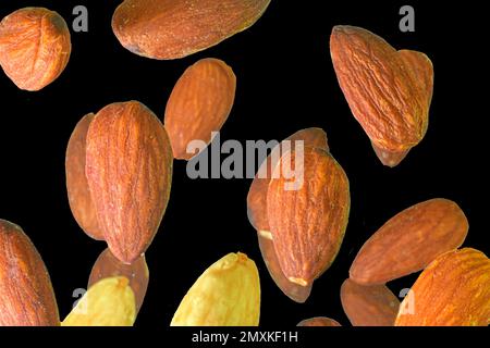 Falling almond isolated on a black background, selective focus. Almond nuts levitate on a black background. Freeze motion of flying whole almonds. Stu Stock Photo