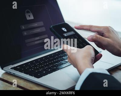 Two steps authentication (2FA) concept. Shield icon and password code showing on smart phone screen while businessperson login on laptop computer, Ide Stock Photo