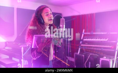 Technology, singing or woman on neon studio microphone, music lyrics or songwriting app in night recording. Singer, musician or artist on tablet in Stock Photo