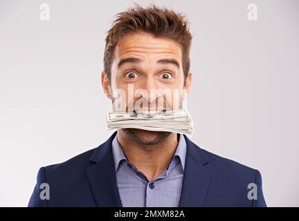 Eager to make money. Studio shot of a businessman with money stuffed in his mouth. Stock Photo