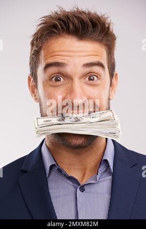 He got greedy. Studio shot of a businessman with money stuffed in his mouth. Stock Photo
