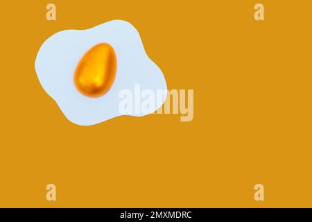 Creative layout made of scrambled eggs with decorated golden Easter eggs on a yellow background. Minimal Spring holidays concept. Stock Photo