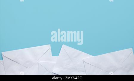 A stack of white envelopes on blue background with copy space. Stock Photo