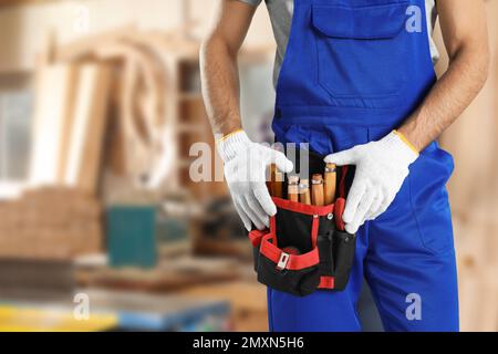 Carpenter with tool belt in workshop, closeup Stock Photo