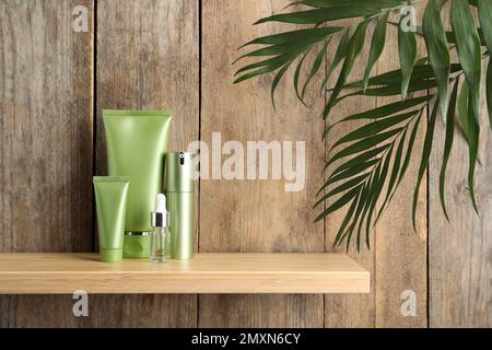 Set of cosmetic products on shelf near wooden wall Stock Photo
