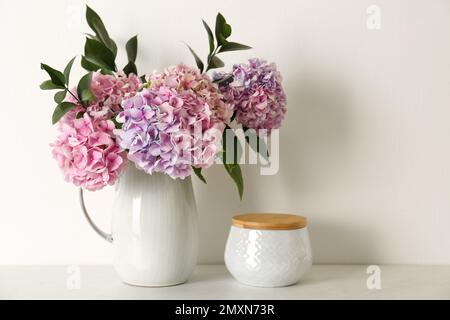 Bouquet with beautiful purple hydrangea flowers and jar on light countertop Stock Photo