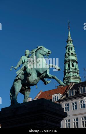 Equestrian statue of Bishop Absalon (founder of Copenhagen), with spire of St Kunsthallen Nikolaj Church, Højbro Plads square, Copenhagen, Denmark Stock Photo