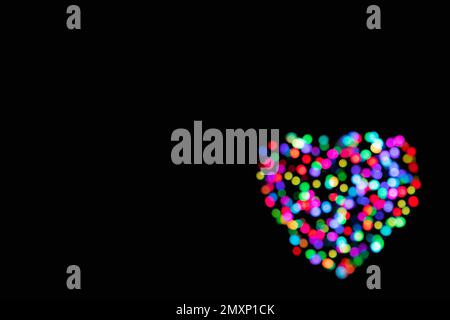 Background of defocused rainbow colours lights in the shape of a heart with copy space for Valentines Day Stock Photo