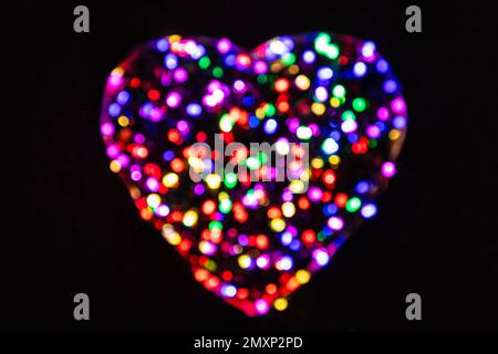 Multicolored defocused circles from the light in the shape of a heart on a black background Stock Photo