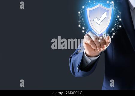 Cyber insurance concept. Man using virtual screen with shield illustration as symbol of protection, closeup Stock Photo