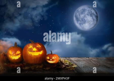 Spooky pumpkin head jack lanterns under full moon on Halloween. Space for text Stock Photo