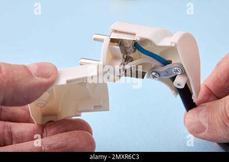 An electrician connected an electrical cord to collapsible European standard electrical plug. Stock Photo