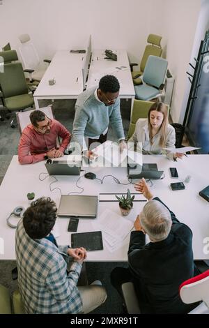 Five businesspeople discussing about their upcoming job at the office Stock Photo