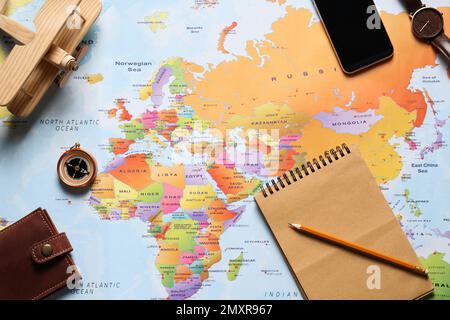 Flat lay composition with notebook and different items on world map. Trip planning Stock Photo