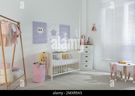 Baby room interior with cute posters, crib and clothing rack Stock Photo