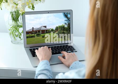 Woman choosing new house online using laptop or real estate agent working at table, closeup Stock Photo