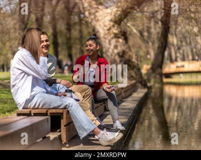Full length portrait of cheerful college student talking to friends outdoors in campus Stock Photo