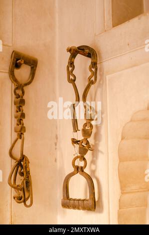 A vertical shot of a vintage pair of shackles for prisoners hang on the wall Stock Photo