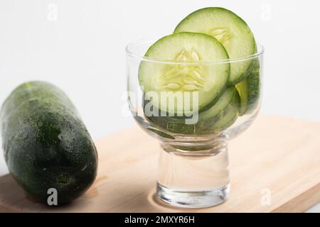Sliced cucumbers in a transparent cup on a white background. Stock Photo