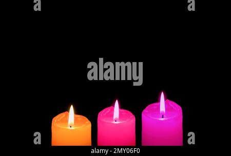 Burning Three of Different Vibrant Colors Candles on Black Backdrop with Copy Space Stock Photo