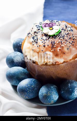 Easter cake decorated with sugar flower and blue painted eggs on a plate Stock Photo