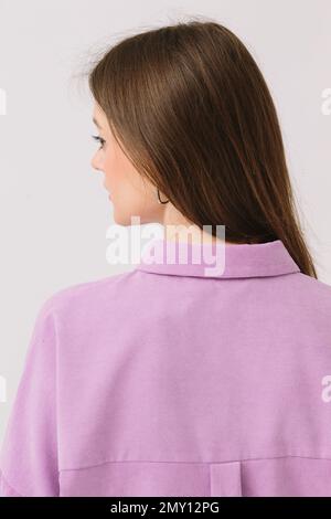 Photo of a beautiful brunette woman in a colored purple shirt isolated on a white background. Shirt mockup. Stock Photo